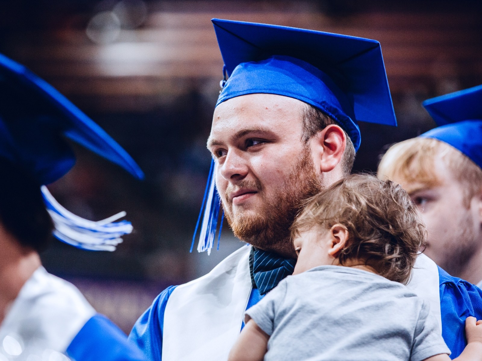 A recent Seattle Colleges graduate cradles a young child at commencement.